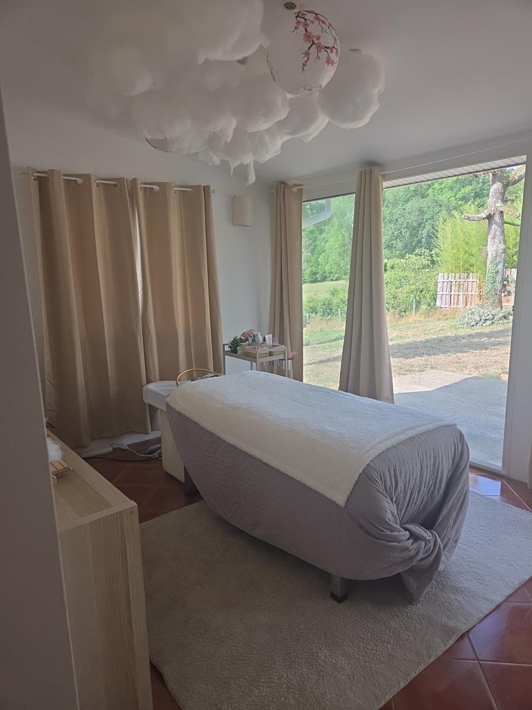 La table de soin devant la baie vitrée ouverte sur la verdure